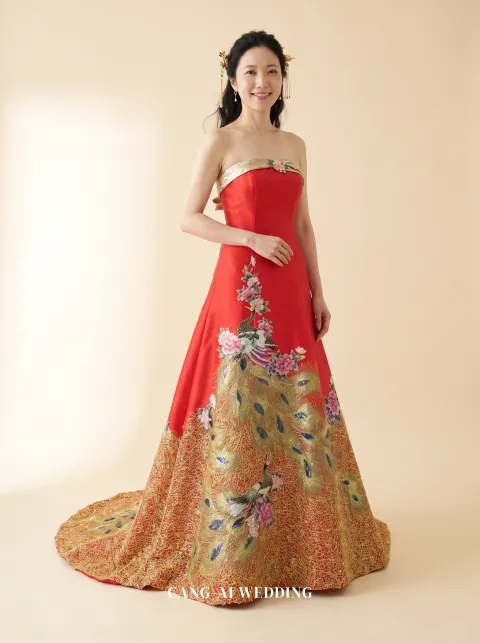 Front full-length of Kaiping, a strapless red A-line gown with a gold sash and peacock skirt, reference 7-NR12.
