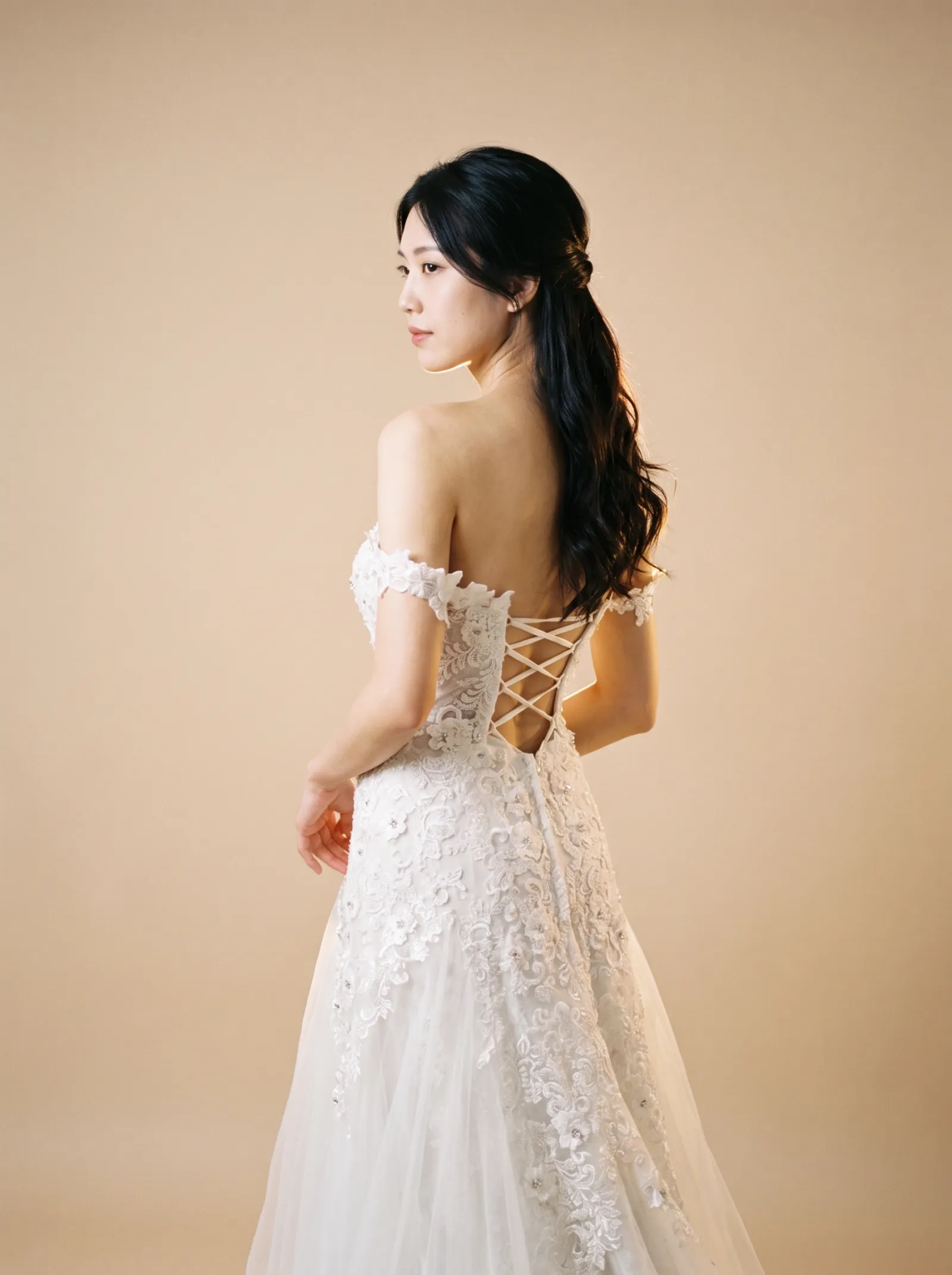 Arabella wedding gown, back view showing the laced corset back over bare skin and lace appliqué down the spine