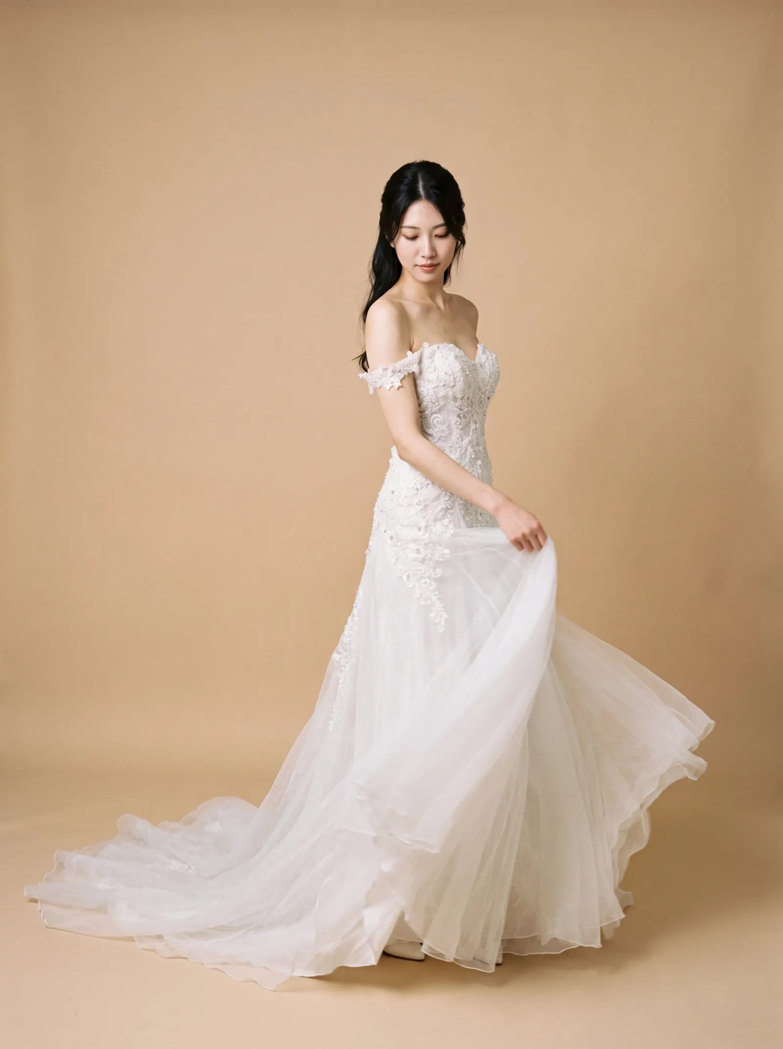 Arabella wedding gown, three-quarter view with the tulle skirt swept to the side, showing the lace bodice and appliqué trailing onto the skirt